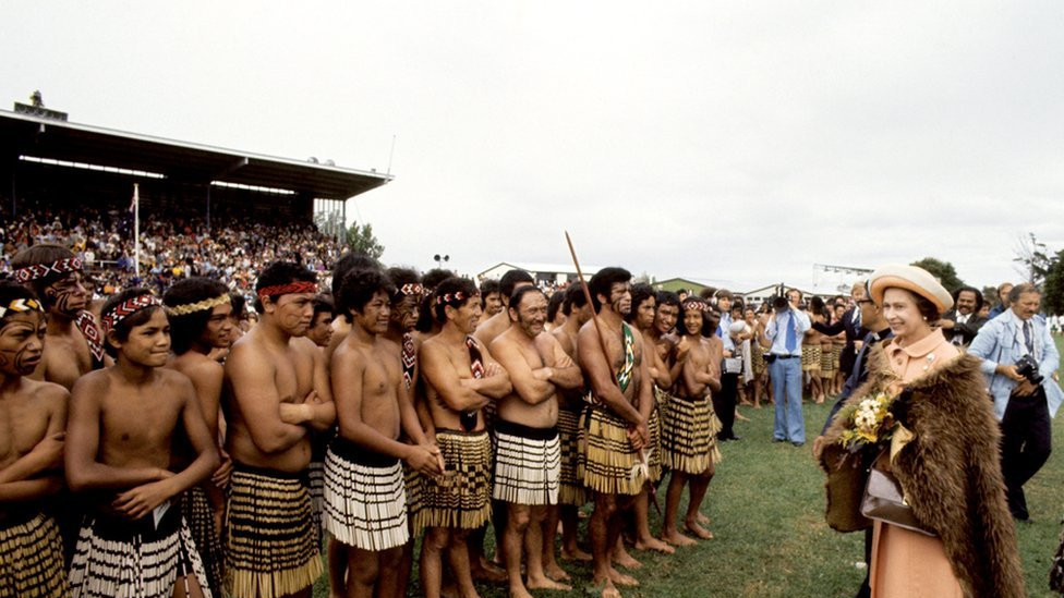 Queen Elizabeth II, wearing a cloak of brown kiwi feathers, with Maori warriors at Rugby Park, Gisborne, when she and the Duke of Edinburgh received a New Zealand Maori welcome at the opening of the Royal New Zealand Polynesian Festival.