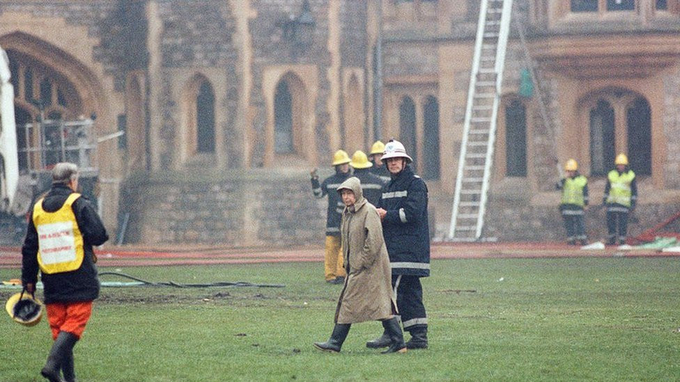 The Queen is escorted by the chief fire officer around the grounds of Windsor Castle as fire fighters battle a fire, 20 November 1992.