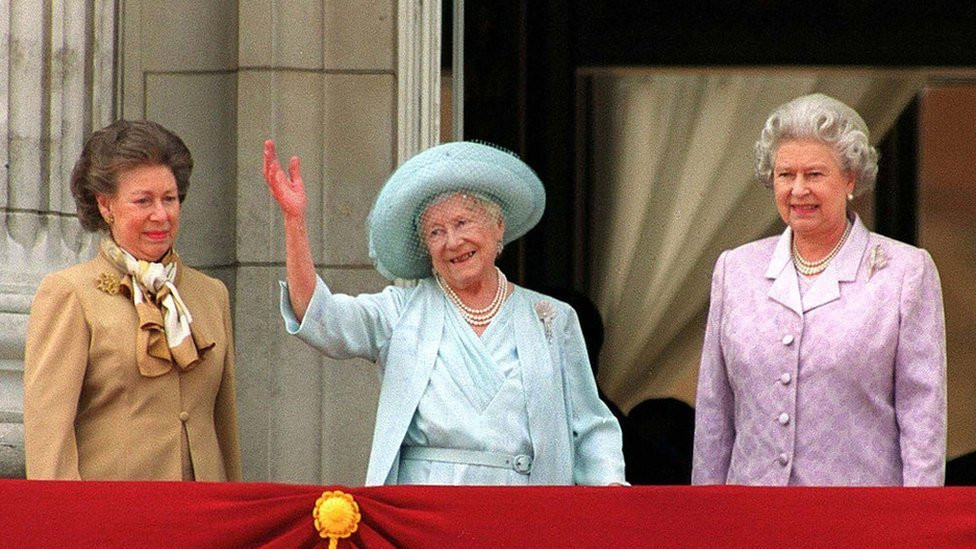 Princess Margaret (L) and Queen Elizabeth (R) stand next to the Queen Mother as she waves to admirers on the occasion of her 100th birthday celebration 4 August, 2000 in London.