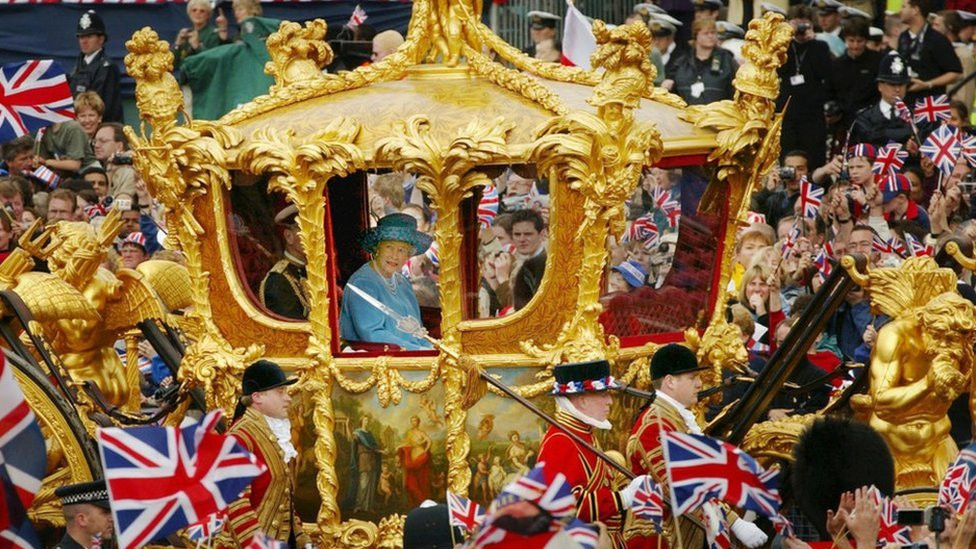 Britain's Queen Elizabeth and Prince Philip ride in the Golden State Carriage at the head of a parade from Buckingham Palace to St Paul's Cathedral celebrating the Queen's Golden Jubilee, on 4 June 2002, along The Mall in London.