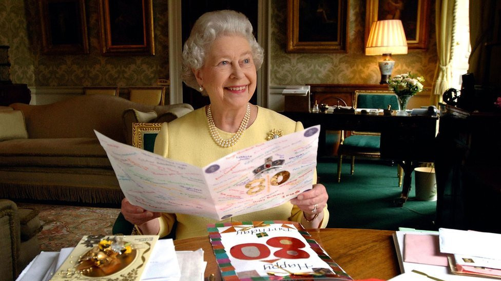 Queen Elizabeth II sits in the Regency Room at Buckingham Palace in London as she looks at some of the cards which have been sent to her for her 80th birthday