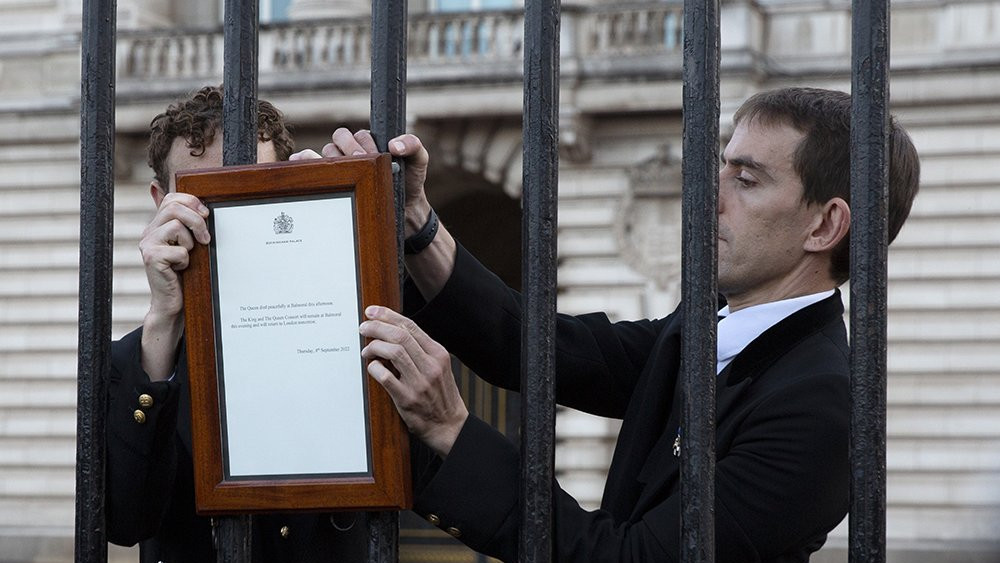 Članovi kraljevskog domaćinstva postavljaju obaveštenje na kapiji Bakingemske palate u Londonu, na kojem stoji vest o smrti kraljice Elizabete Druge