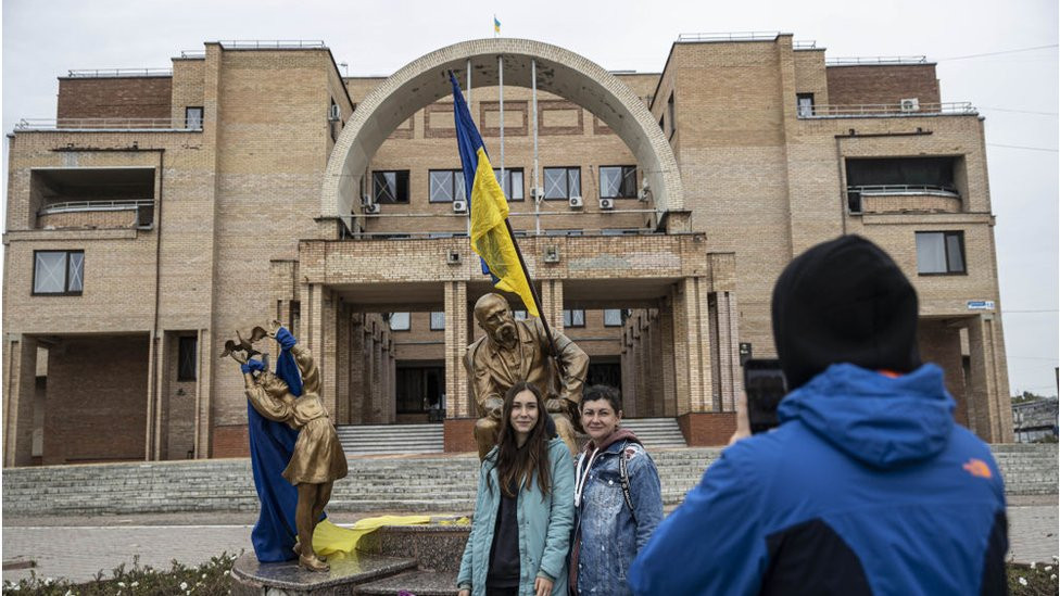 People pose in front of Taras Shevchenko statue with an Ukrainian after Ukrainian army liberated the town of Balakliya in the southeastern Kharkiv region, Sept 11, 2022