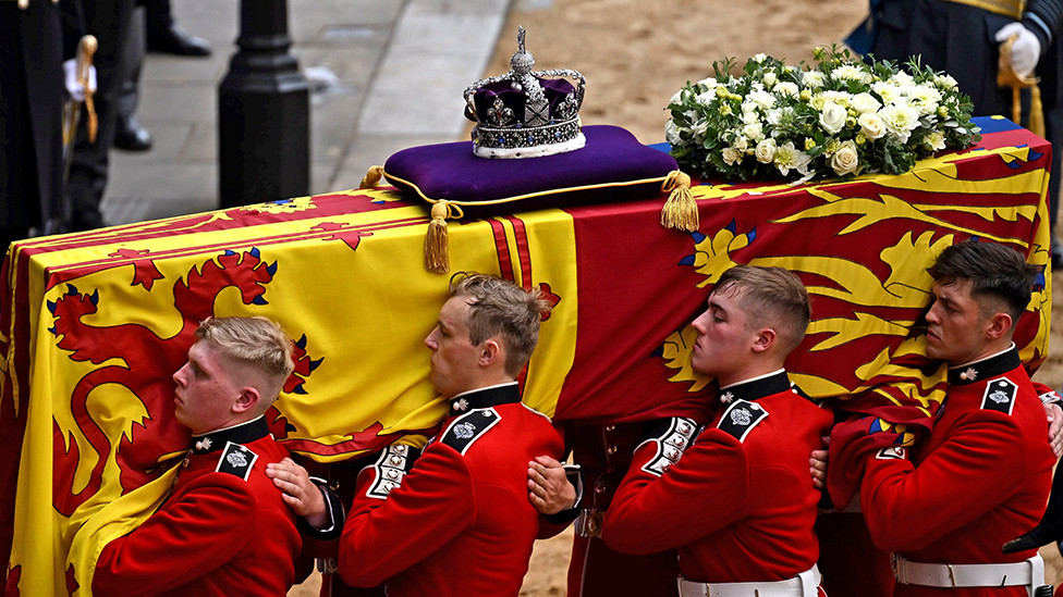 The Bearer Party from Queen's Company, 1st Battalion Grenadier Guards, carries the coffin of Queen Elizabeth II, draped in the Royal Standard with the Imperial State Crown placed on top, into Westminster Hall, London on 14 September 2022