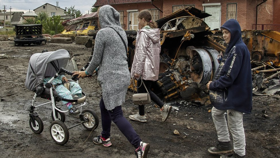 People walk past a damaged tank in Izyum, north-eastern Ukraine. Photo: 15 September 2022
