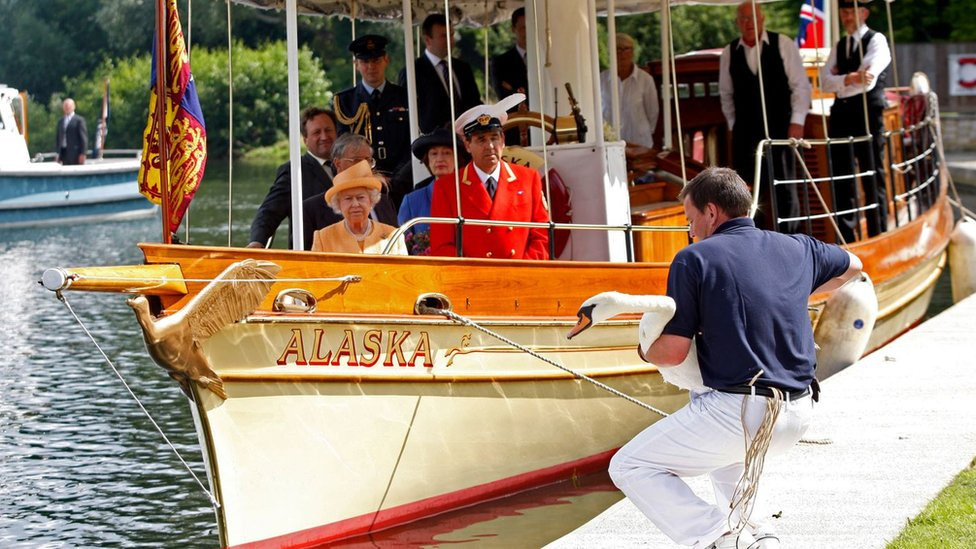 Queen Elizabeth II, accompanied by Swan Marker David Barber (red jacket), watches a swan upping census from a boat on the River Thames