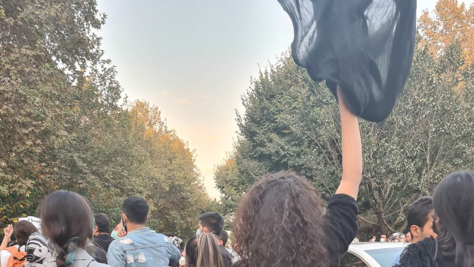 A woman with her hair loose holding a scarf above her head