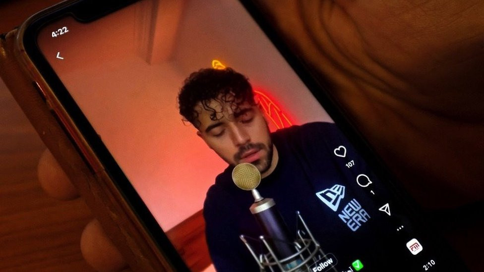 A video of a man singing is shown on a phone