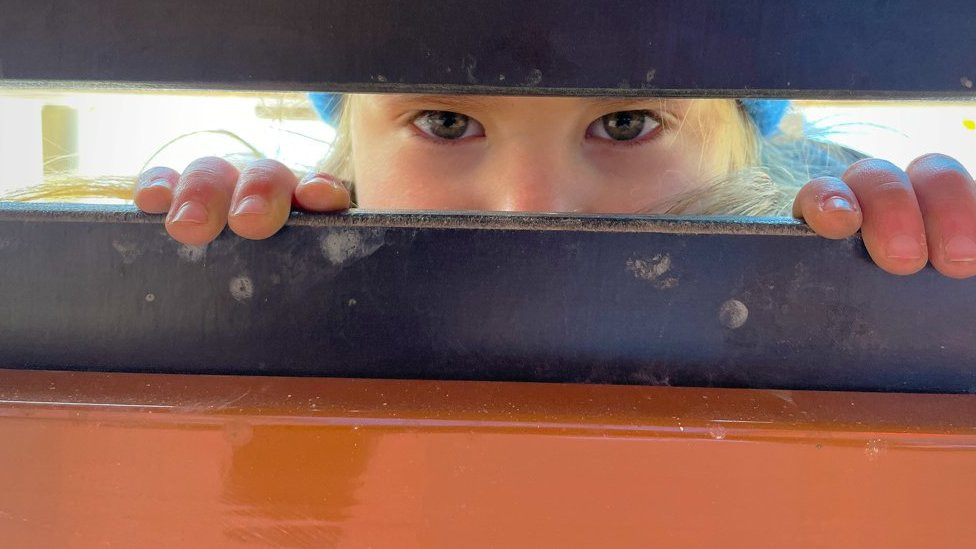 Ksusha looks through a door