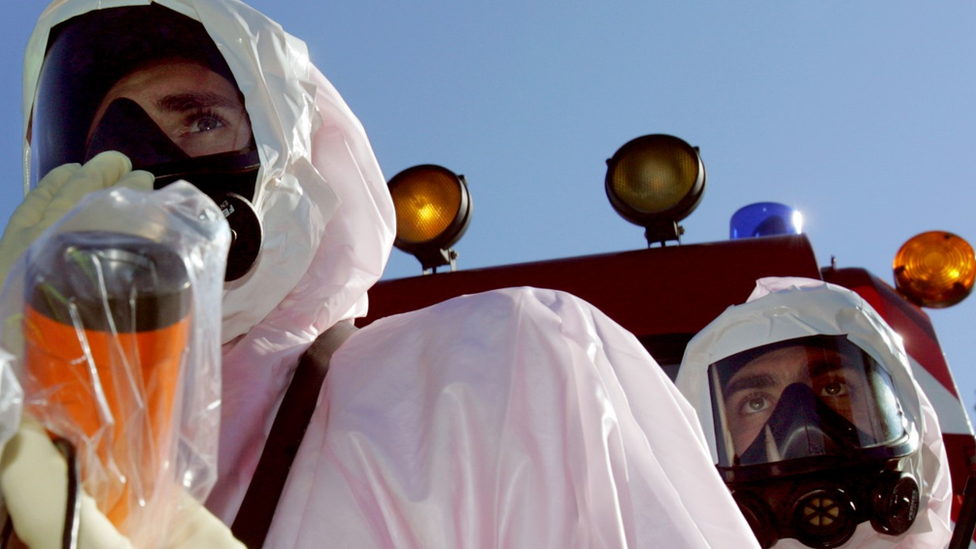 Emergency workers in hazm,at suits with a Geiger counter