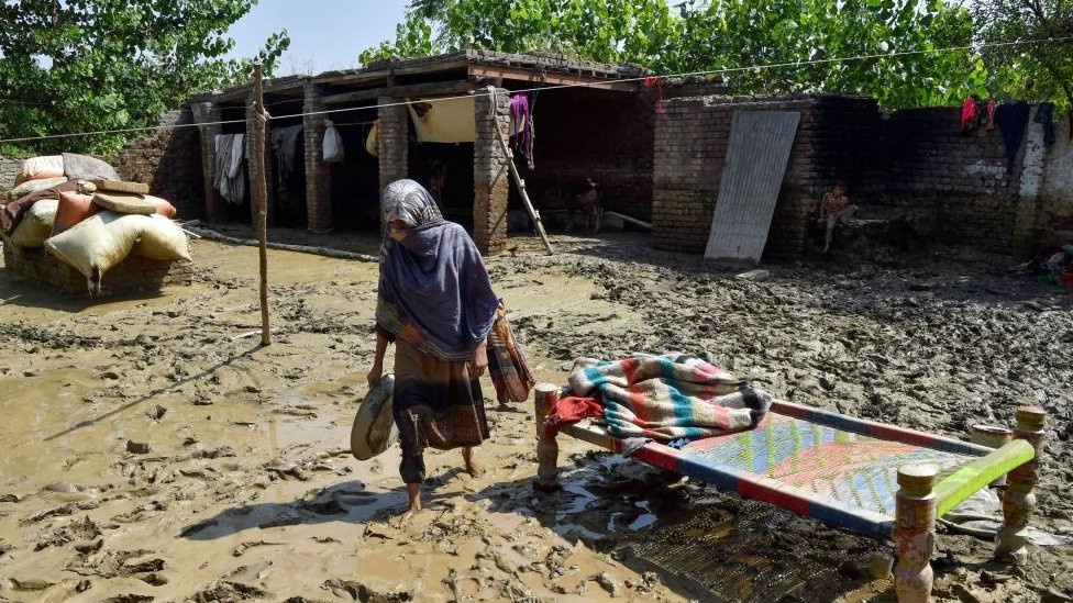 A flood-affected woman walks outside her damaged house at Jindi village in Charsadda district of Khyber Pakhtunkhwa on September 1, 2022.