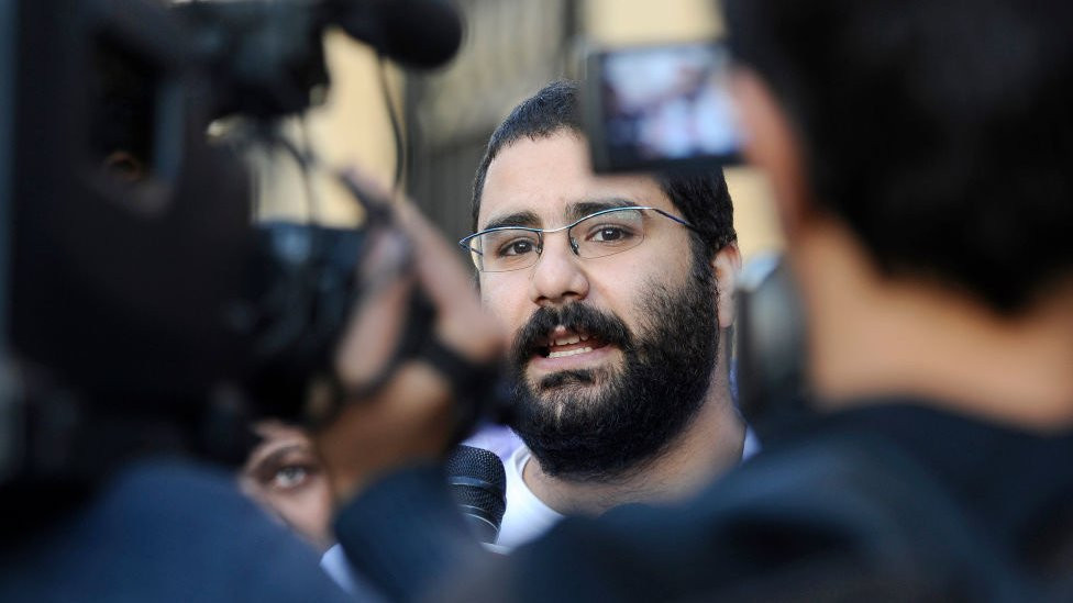 Alaa Abdel Fattah speaks as various cameras film him