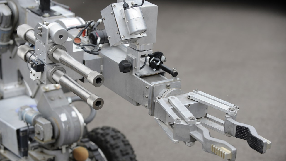 A bomb disposal robot extends its arm