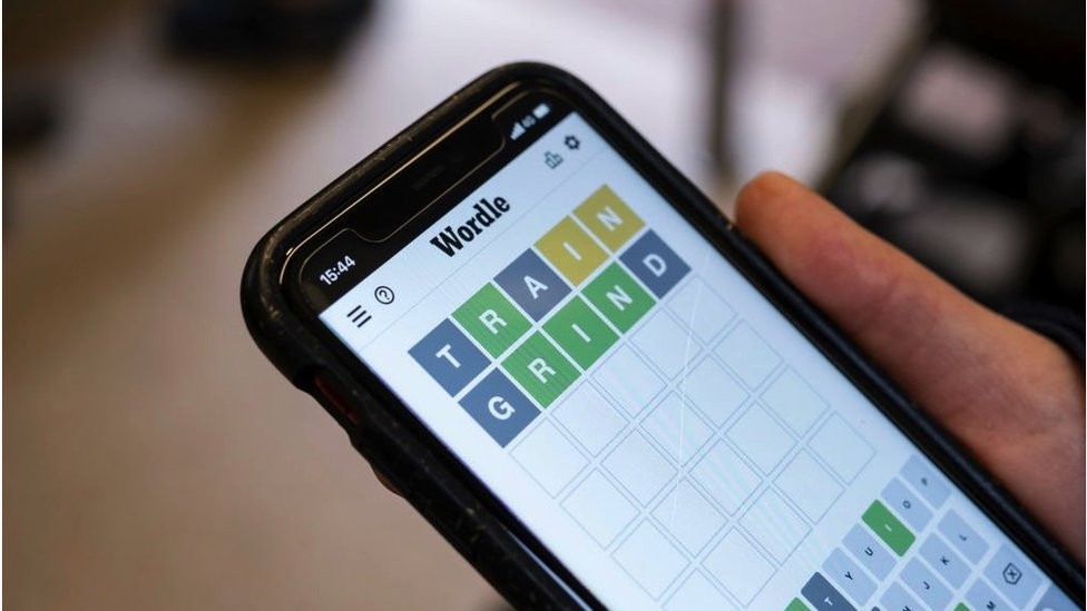 A woman playing Wordle on her phone onboard a London tube train