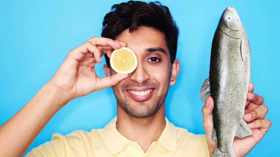 Man holding up a fish and a lemon
