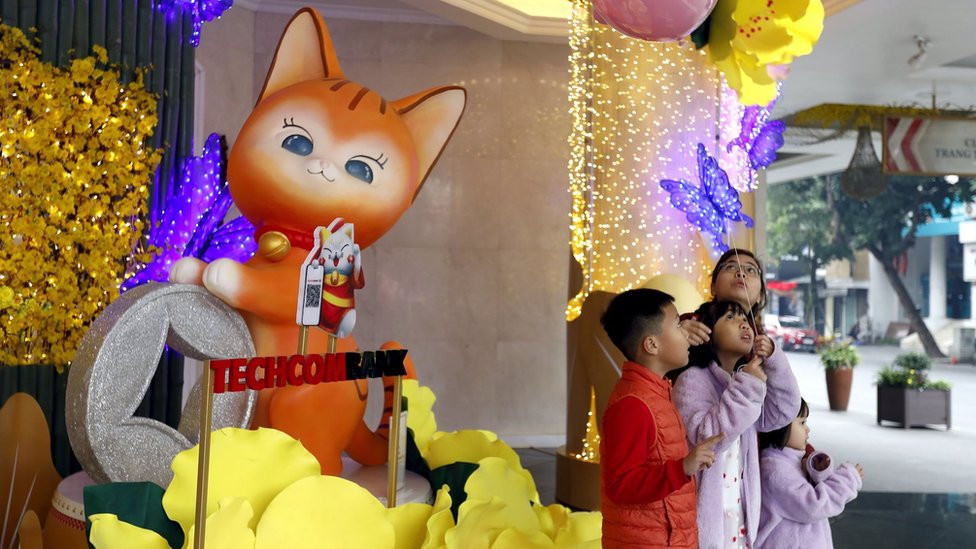 Children pose for a photo in front of a display of butterflies and a cat