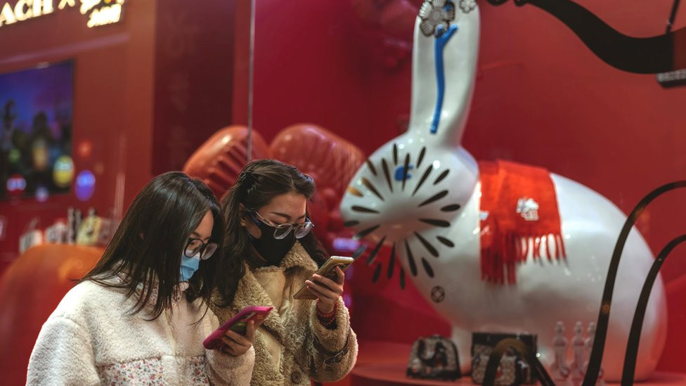 Two women wearing face masks in front of a pottery rabbit shop for the upcoming Chinese Lunar New Year in a supermarket in Beijing, China on 11 January 2023
