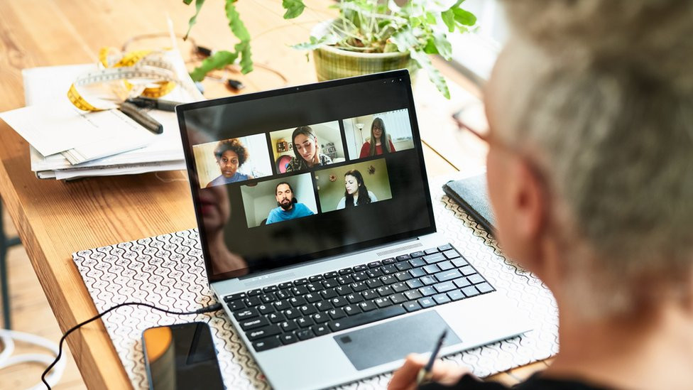 A man looking at a Zoom screen with participants on