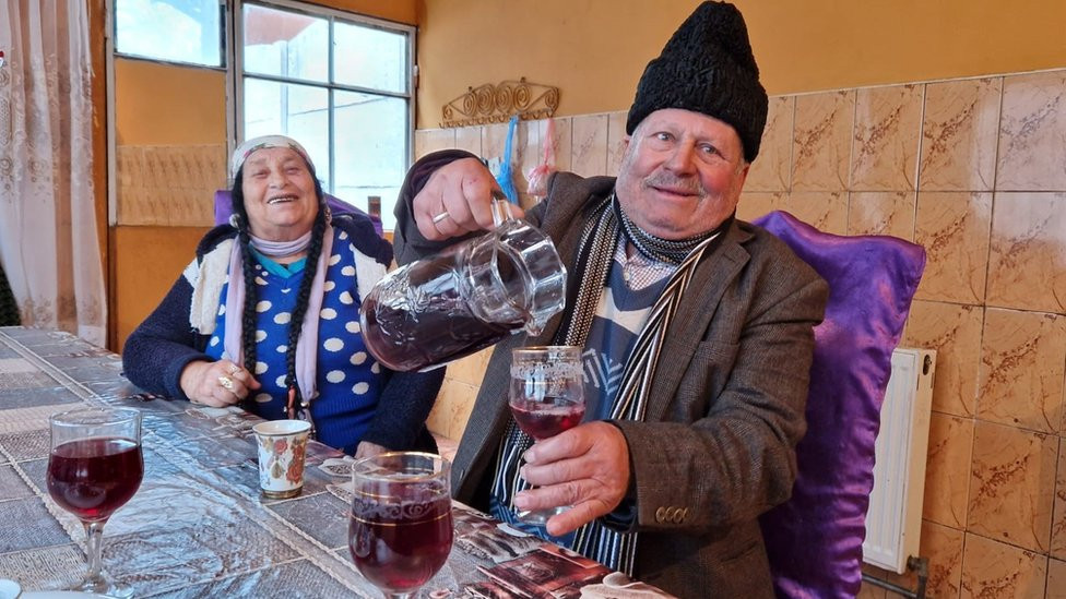 Hinta Gheorghe with his wife Agripina Hirta. Hinta pouringi wine.