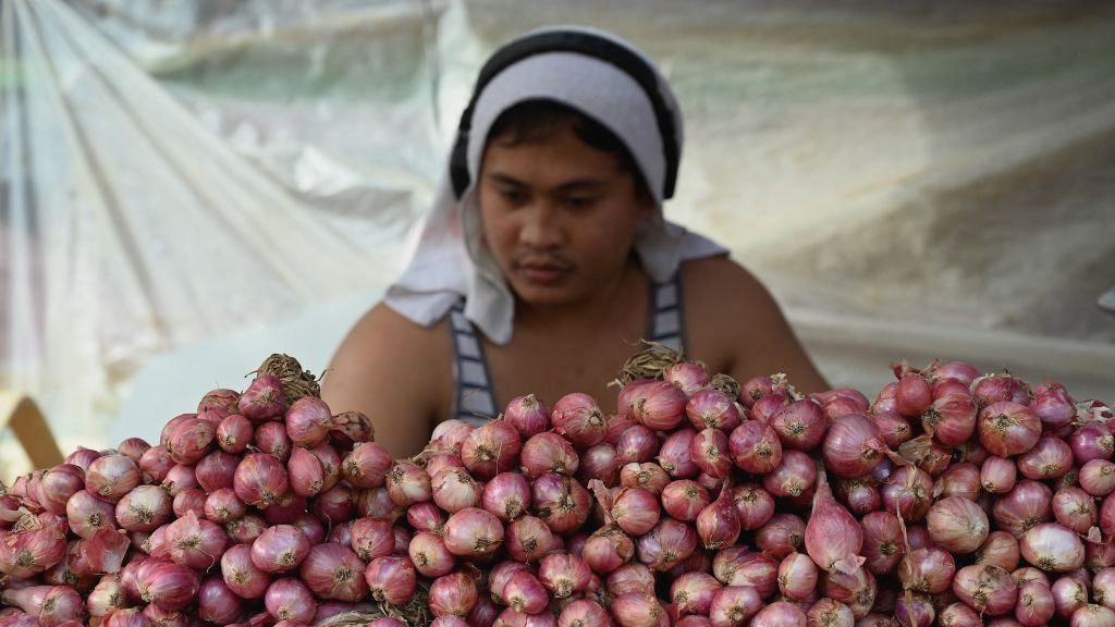 A vendor sells onions at a market in Manila.