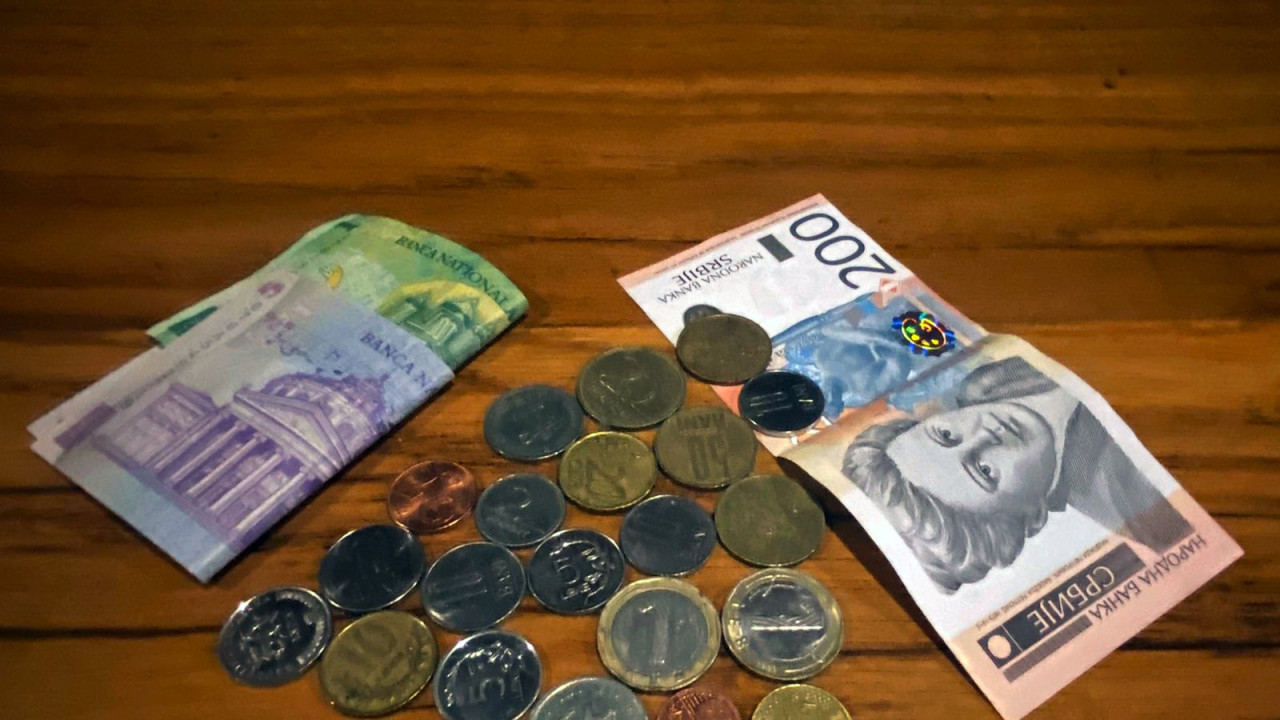 Rumunske, hrvatske, albanske, bugarske, makedonske i mađarske kovanice na stolu, sa paprirnim dinarima i rumunskim lejima