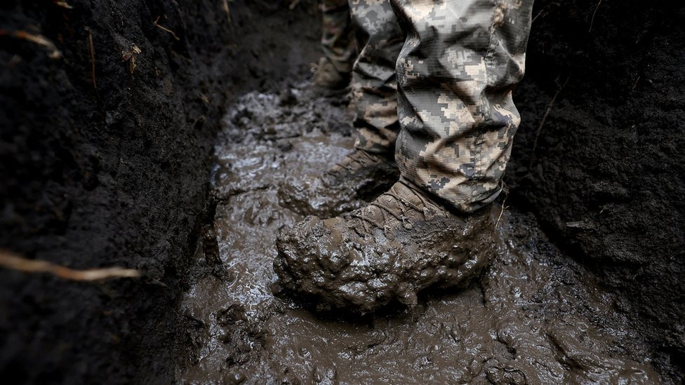 A Ukrainian serviceman's boot standing in mud in a trench near the frontline