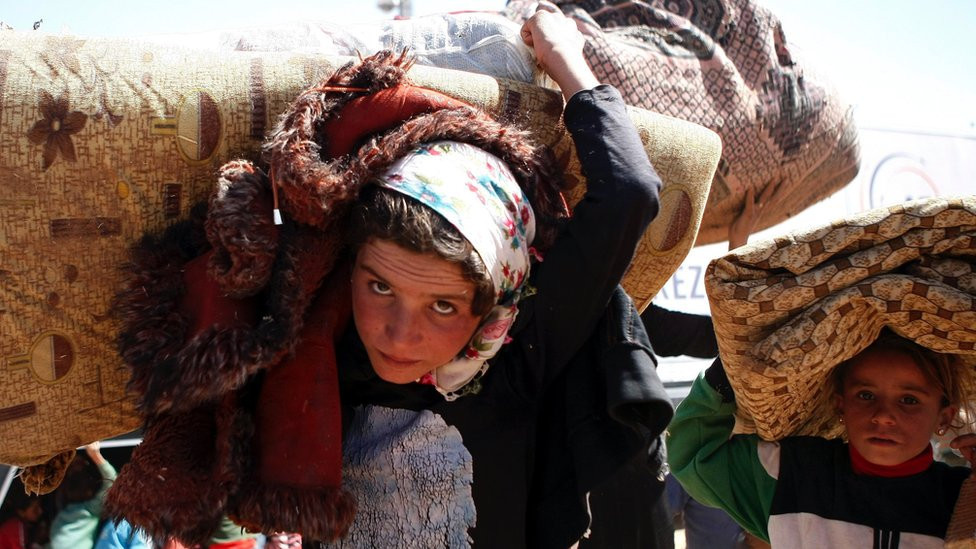 Syrian Kurds flee the Islamic State (IS) militant group by crossing into Turkey at the Yumurtalik crossing gate on 23 September 2014