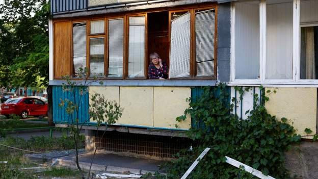 žena razgovara telefonom sa terase oštećenog stana