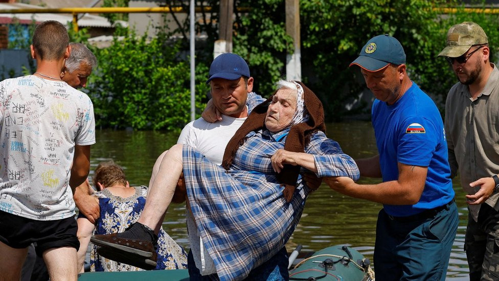 A man carrying an elderly woman in flooded Kherson