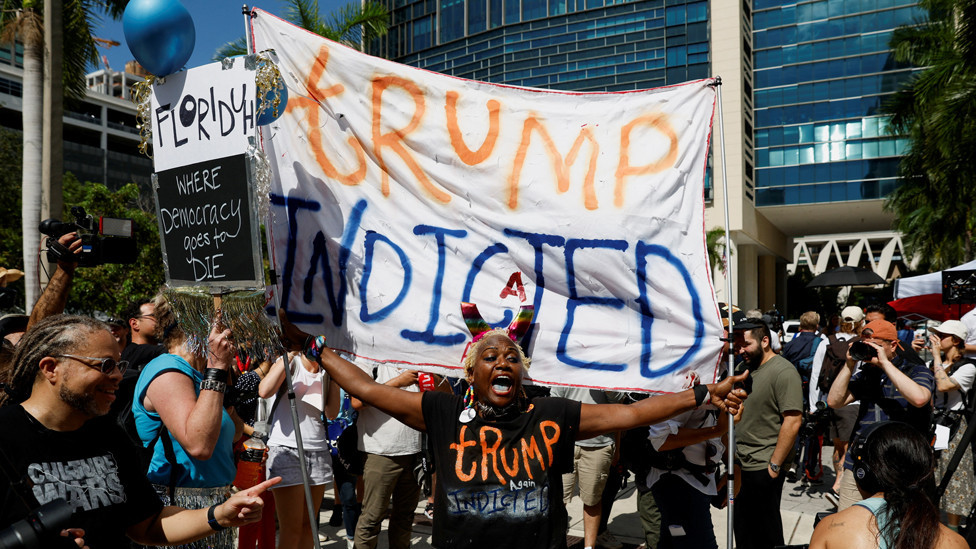 A person holds a banner near The Wilkie D. Ferguson Jr. United States Courthouse, on the morning former U.S. President Trump is to appear there on classified document charges, in Miami, Florida, U.S., June 13, 2023