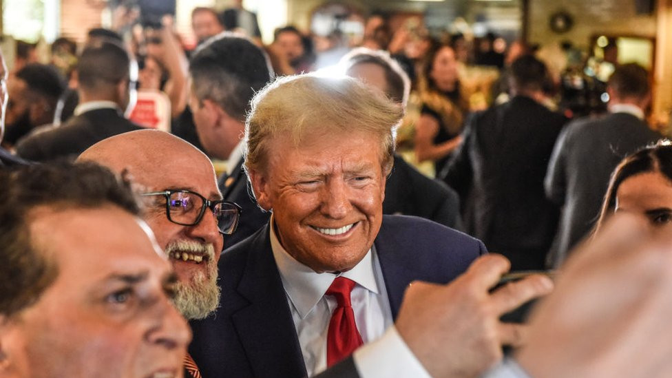 Donald Trump poses with patrons during a surprise visit to the Versailles restaurant in Little Havana, Miami, after pleading not guilty in court