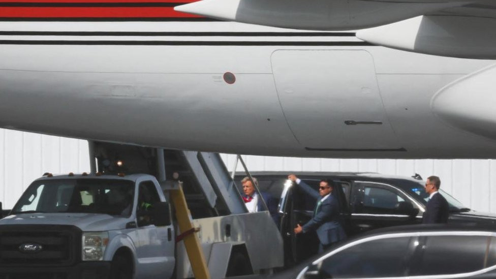 Donald Trump is pictured climbing the stairs of his plane to leave Miami, as an aide holds a car door open on the runway behind him