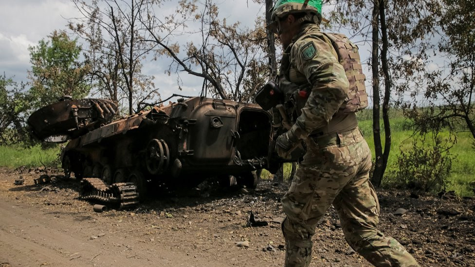 Ukrajinski vojnik trči pored uništenog ruskog borbenog vozila pešadije BMP-2, usred ruskog napada na Ukrajinu, blizu linije fronta u tek oslobođenom selu