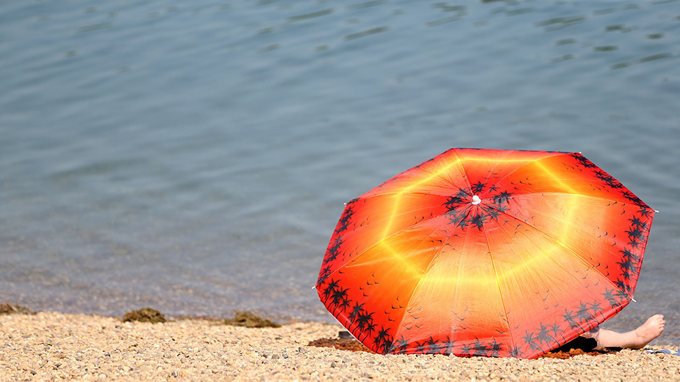 A woman rests under a parasol at the Ada lake in Belgrade, Serbia