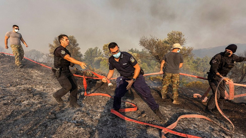 Firefighters, volunteers and police officers move hoses