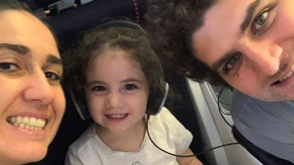 Alexandra Najjar sitting with her parents and wearing headphones