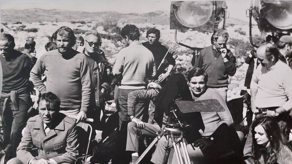 Barton u pauzi snimanja čita knjigu Dnevnik revolucionara, Popović za kamerom, a u uglu Manca Kosir glumica i novinarka iz Ljubljane