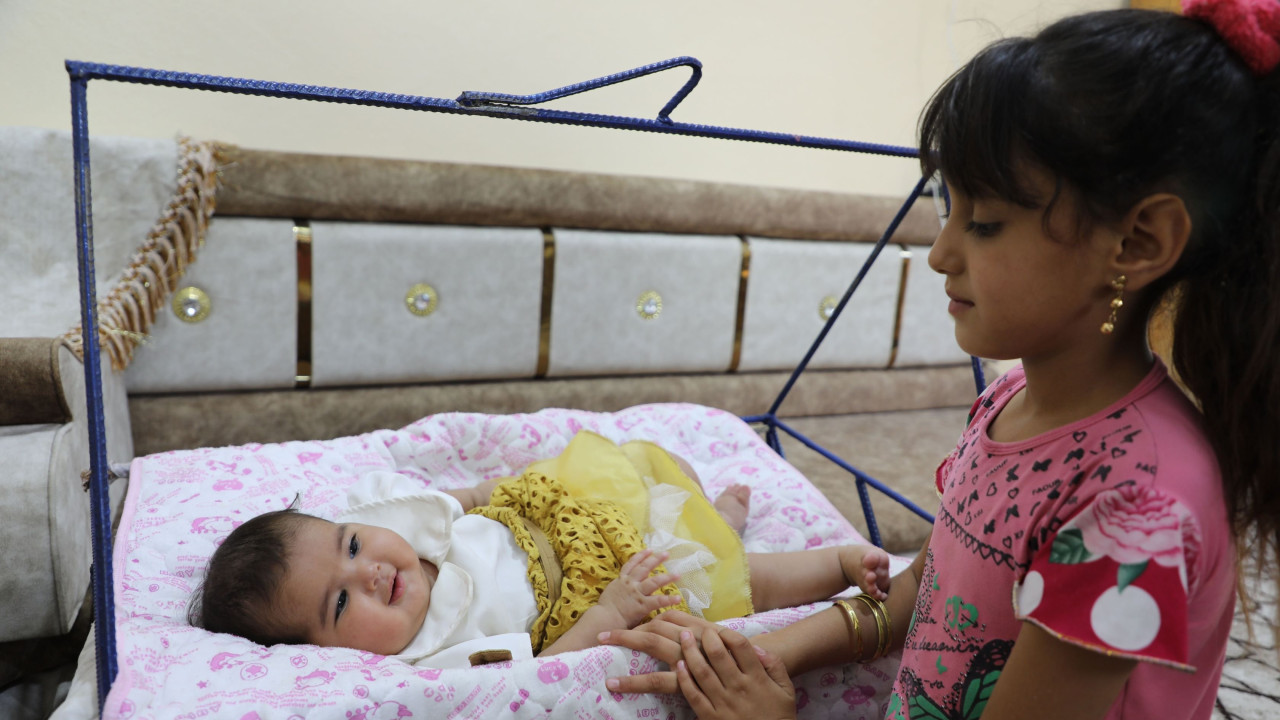 Baby Afraa on a swing being attended by her cousin