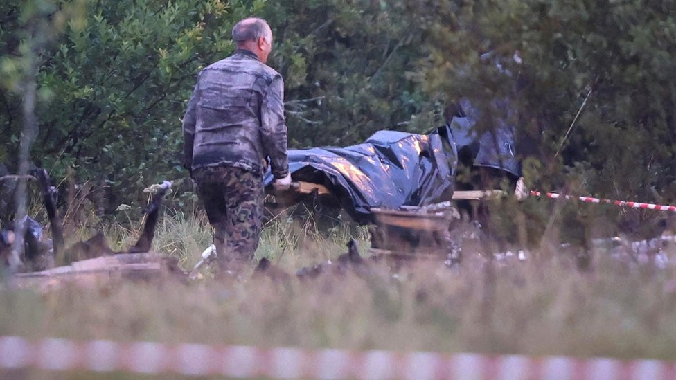 Emergency specialists carry a body bag from the wreckage of a private jet