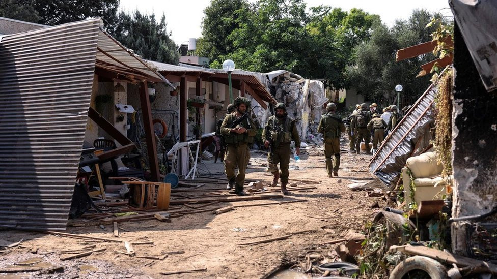 Israeli soldiers walk through the remains of a residential area of Kibbutz Kfar Aza, in southern Israel