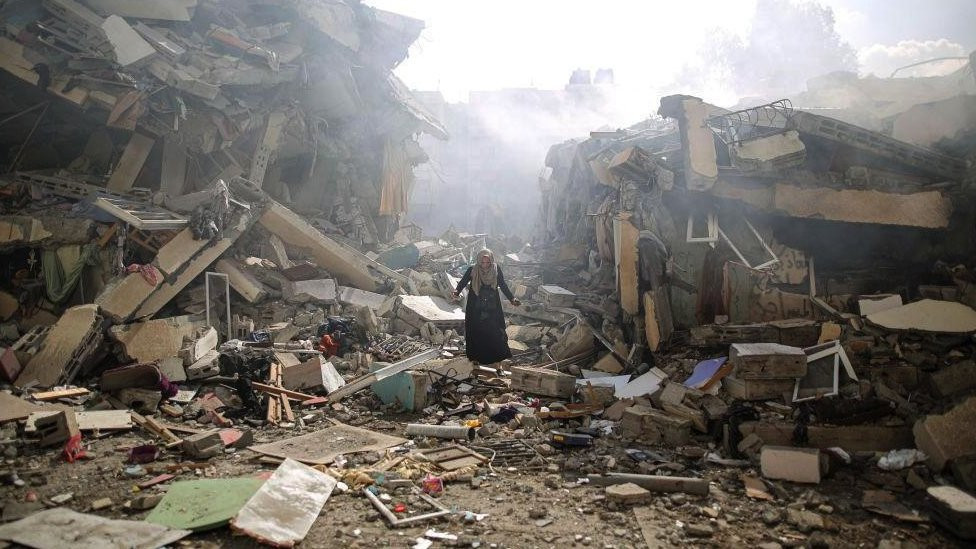 A resident gets upset as she walks amid near the rubble of residential buildings after Israeli airstrikes at al-Zahra neighbourhood in Gaza Strip on 19 October 2023.