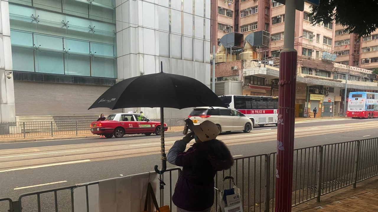 A woman is seen from behind demonstrating in front of a large office building