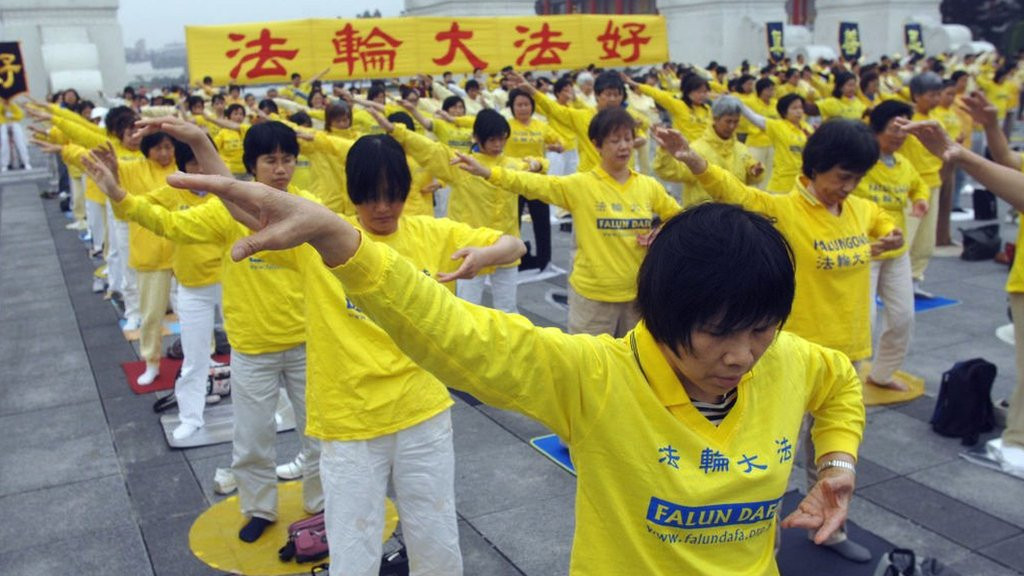 A large group of Falun Gong practitioners make co-ordinated body movements