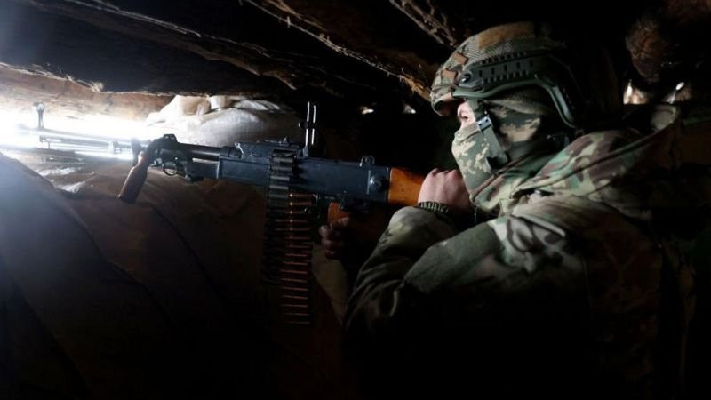 Soldier with rifle peers through slit