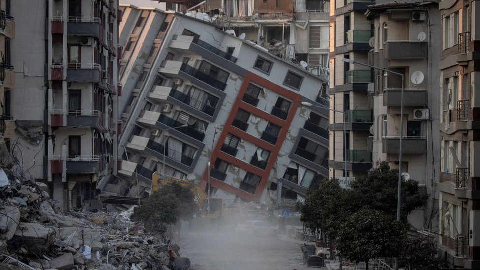 A woman walks on a street amid destroyed buildings on February 17, 2023 in Hatay, Turkey.