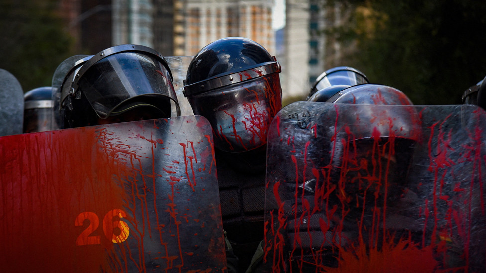 Police officers stand guard with their shields covered in red paint during a protest held by teachers against a new curriculum established by Bolivia's Ministry of Education, in La Paz, Bolivia, April 10, 2023.