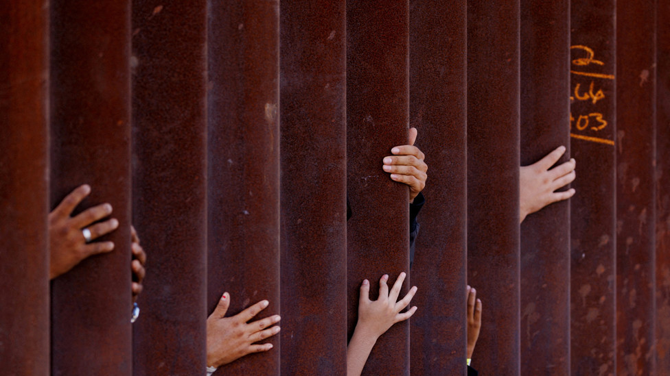 Migrants wait for some food from an aid worker after gathering between the primary and secondary border fences between Mexico and the United States as they await processing by U.S immigration in San Diego, USA. September 12, 2023.