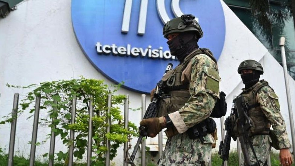 Armed police stand guard in front of the studios