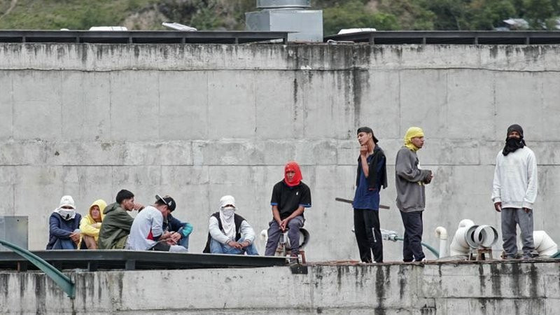 Prison inmates stand guard on a roof