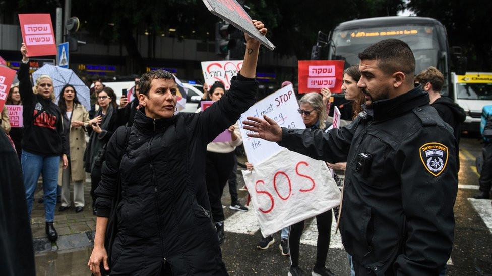 An Israeli police officer tries to disperse protesters during a demonstration in Tel Aviv on 24 January 2024 calling for the immediate release of all Israeli hostages and a ceasefire in Gaza